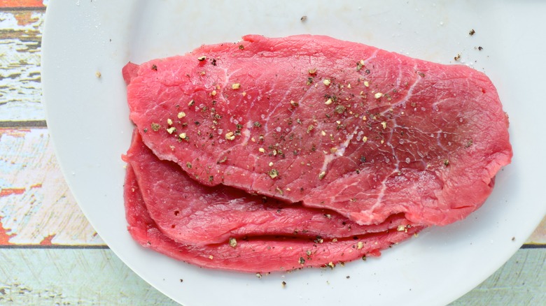 Raw seasoned minute steak on a plate