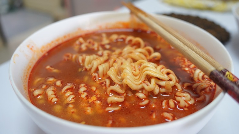 A bowl of spicy-looking ramen with chopsticks on the side.