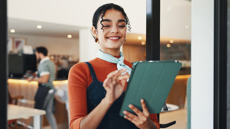 Smiling restaurant employee looking at iPad