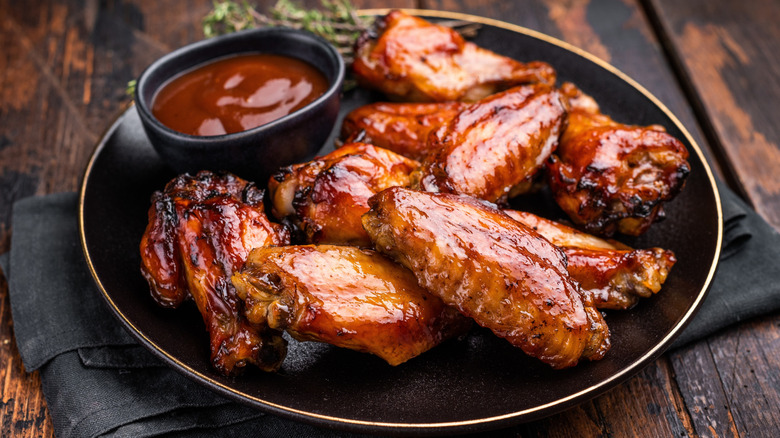 Cooked chicken wings on a black plate with sauce