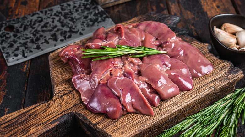 Raw chicken liver (a kind of offal) on a wooden cutting board.