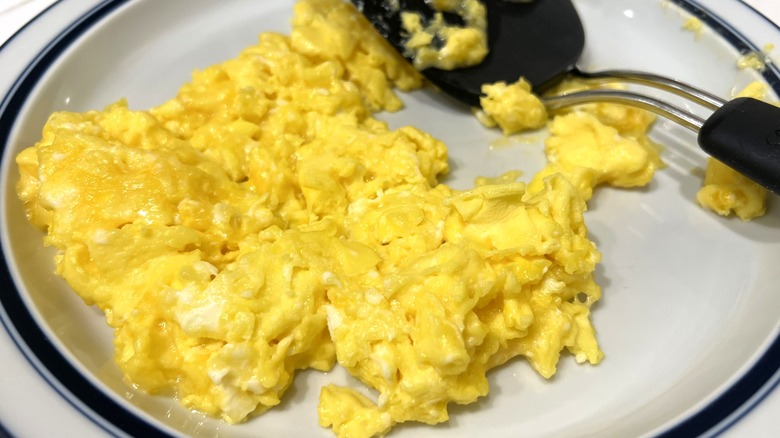 Fluffy scrambled eggs on a plate with a spatula