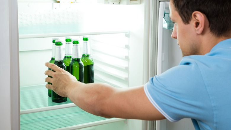 Person taking beer bottle from fridge