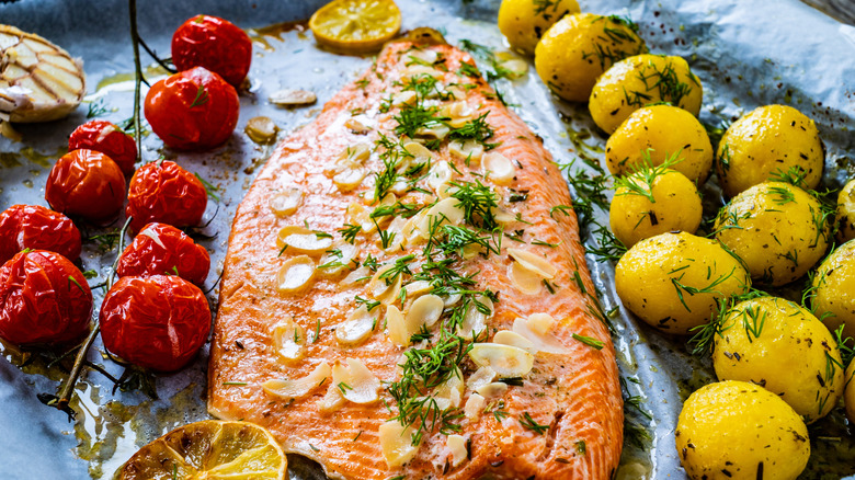A sheet pan topped with trout, potatoes, and tomatoes
