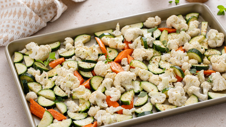 A sheet pan veggies being seasoned