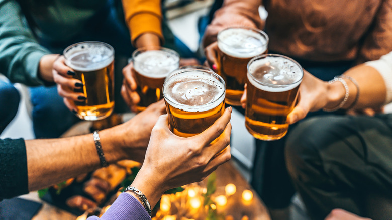 Five arms cheersing their glasses of beer in a circle.