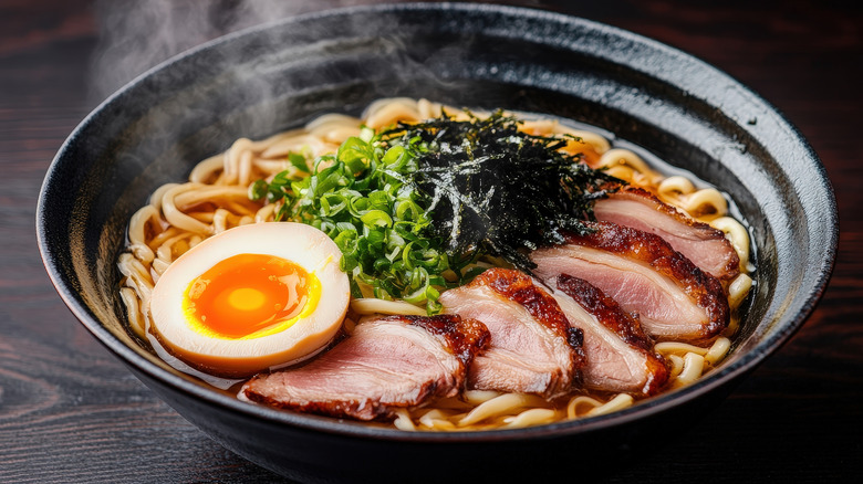 A bowl of Japanese ramen with a soft-boiled egg, seaweed, and pork