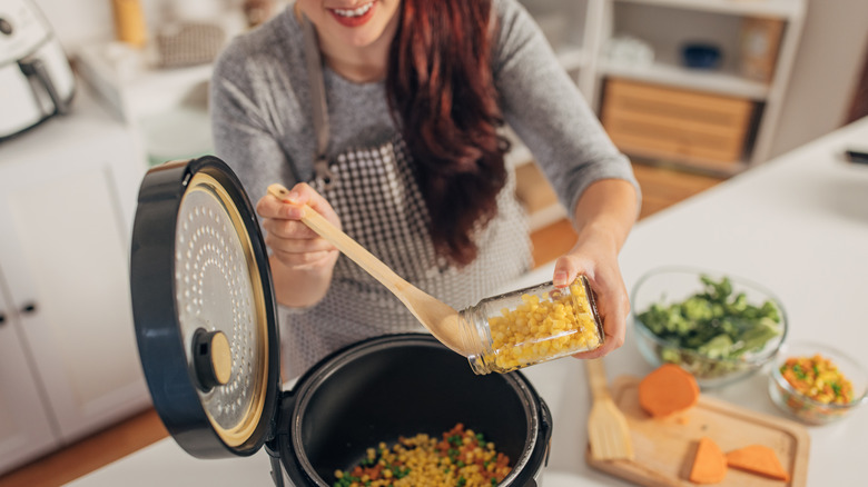 woman pouring ingredients into slow cooker
