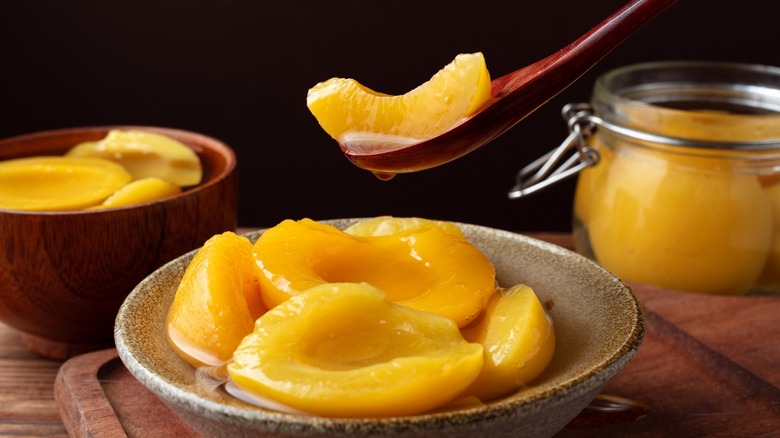 Canned peaches in bowl and in spoon