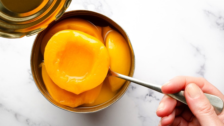 Person lifting canned peach from can