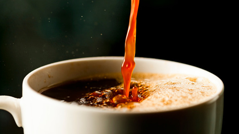 Black coffee being poured into a white cup