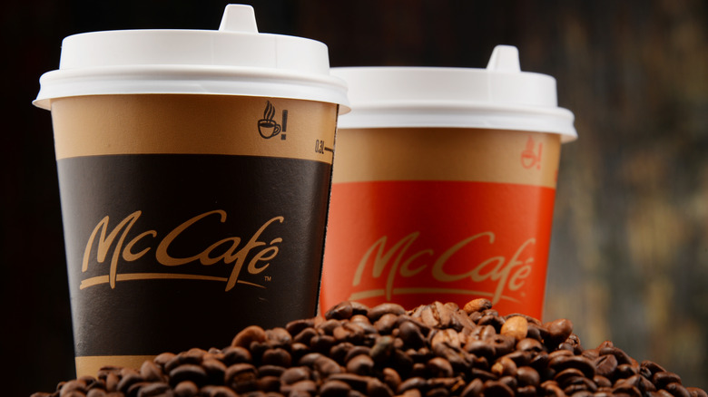 Two to-go McCafé coffee cups near a small pile of coffee beans