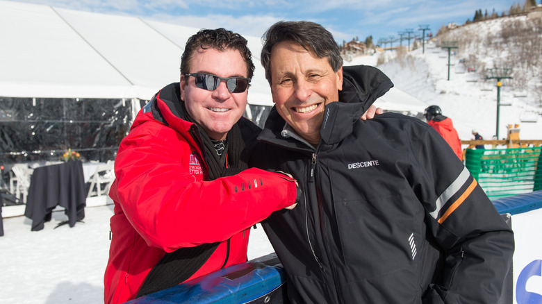 Schnatter, in sunglasses and a red Papa Johns ski jacket, poses with another attendee at a celebrity skiing fundraiser.