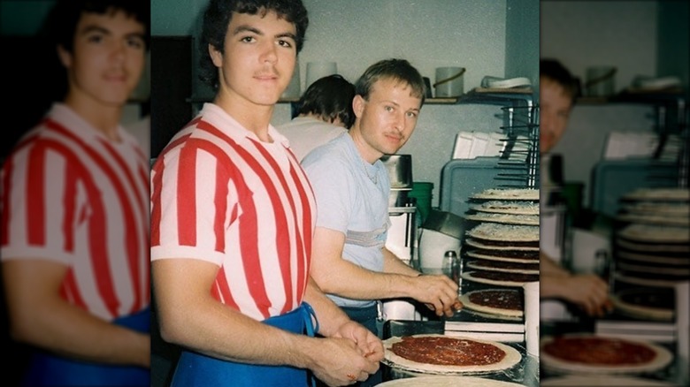 John Schnatter in red and white striped shirt makes pizzas with a colleague in the first Papa Johns location.