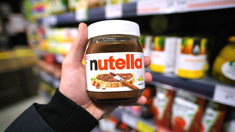 A person holding a jar of Nutella.