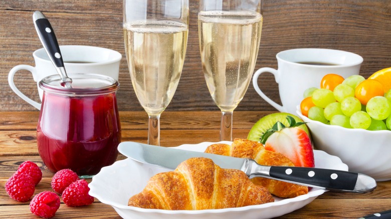 Croissants, fruit, champagne, and coffee cups in brunch setting