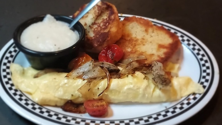 Greek white smoked chicken omelet with a biscuit and grits from Demetri's on an oval platter with a black checkered rim