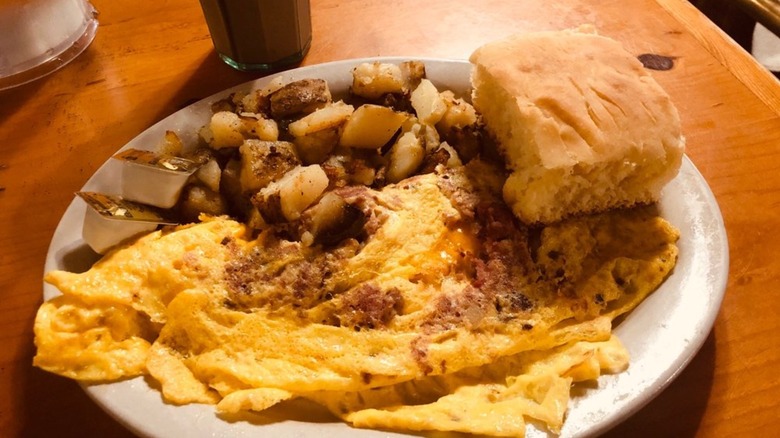 Corned beef hash and cheese omelette with breakfast potatoes and biscuit from The Coffee Pot Restaurant on a white platter