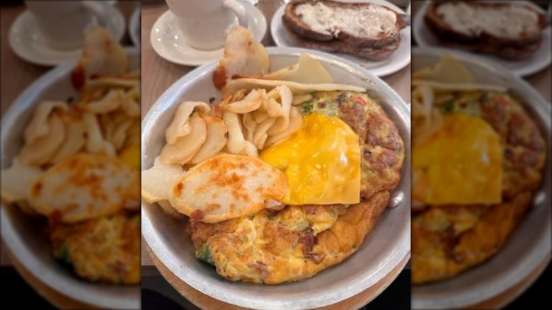 Jumbo Omelette with potatoes from Lou Mitchell's on a white plate with a side of buttered toast and coffee