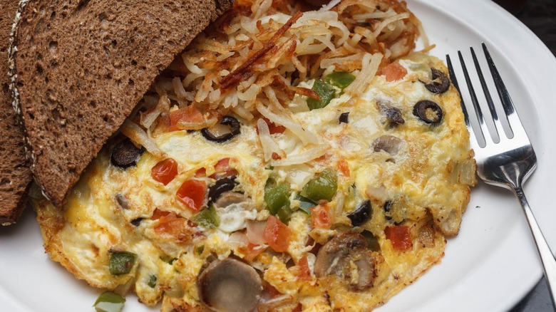 Omelet with side of toast and hash browns from Daisy Dukes on a white plate