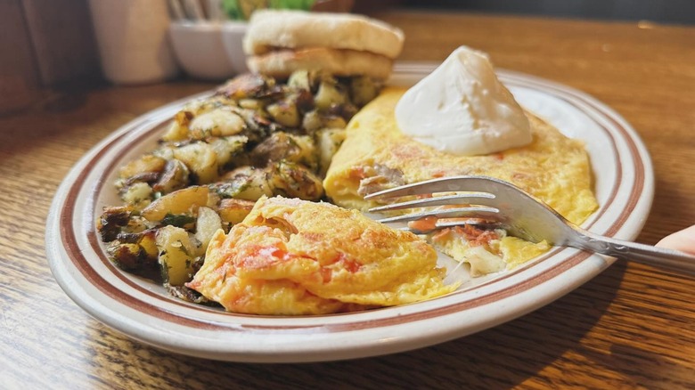 Salmon Omelet special with side of Breakfast potatoes and an English muffin from Echo Lake Cafe on a white platter with a brown striped rim