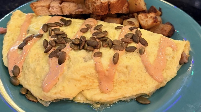 Omelet topped with pumpkin seeds from The Friendly Toast on a blue platter