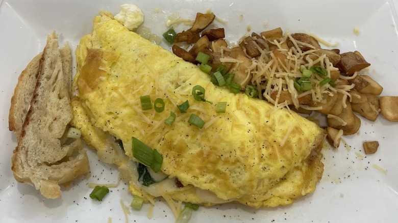 Bacon and spinach omelette with toast and potatoes from Breakfast At Ruiz on a white plate
