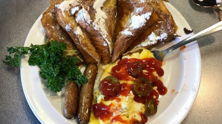 Omelet topped with jalapeños served with sausage and french toast from Joe's Cafe on a white plate