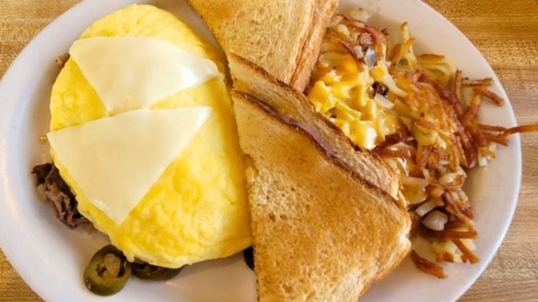 Omelet with jalapeños topped with cheese and served with toast and hash browns from The Omelet Shoppe on a white platter
