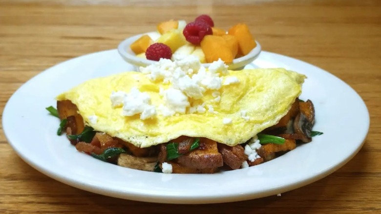 Omelet topped with cheese with side of fruit from from The Wooden Chair on a white plate
