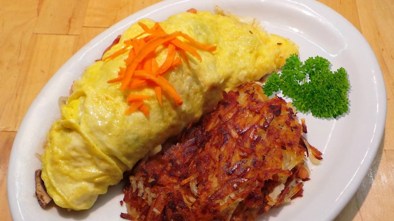 Vegetarian Omelette with side of hash browns and sprig of parsley garnish from The Bunnery Bakery & Restaurant on a white platter