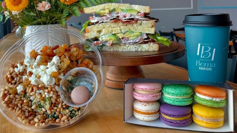 grain bowl with feta and raisins, sandwich, multicolored macarons, and a drink cup