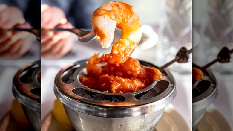 fork holding picking a shrimp out of a shrimp cocktail