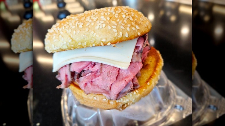 A roast beef sandwich with cheese on a sesame bun