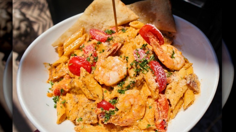 penne pasta with Cajun cream sauce, sausage, red peppers, tomatoes, and herbs with a side of bread