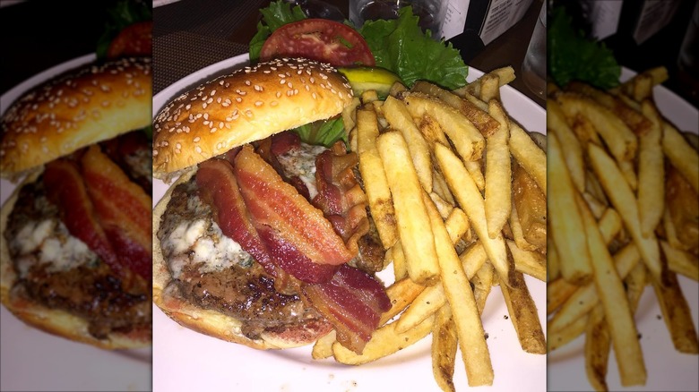 a burger topped with bacon and melted cheese next to fries on a plate