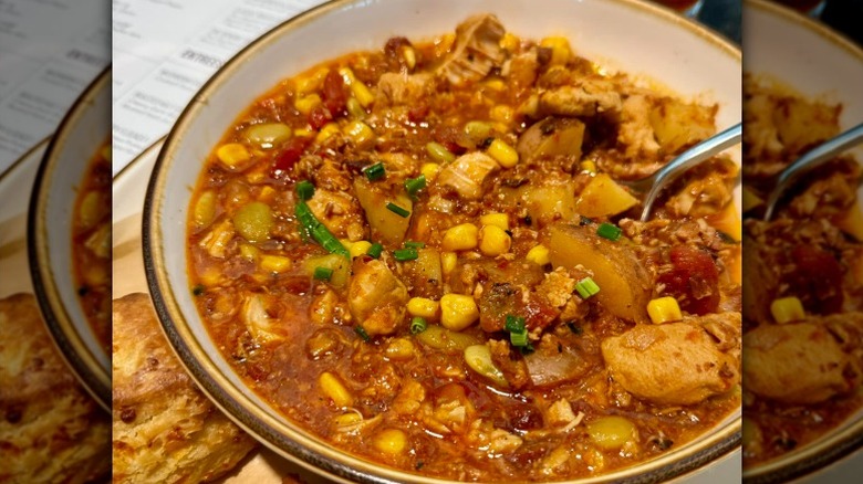 bowl of Brunswick stew with corn, lima beans, potatoes, and chicken, and a side of cheddar biscuits