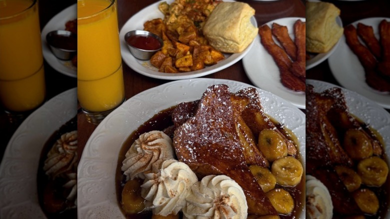 a plate of French toast with caramelized bananas, whipped cream, and powdered sugar, with other plates in the background