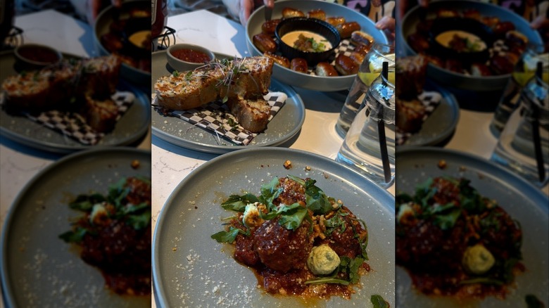 plates with meatballs in marinara sauce, cheesy garlic bread, and pretzel bites on a table