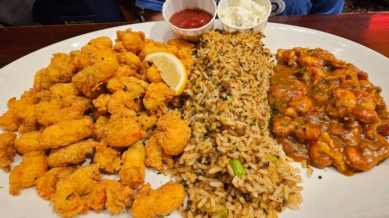large plate with fried crawfish, dirty rice, and crawfish étouffée with dipping sauces on the side