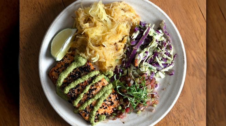 miso sesame trout, spaghetti squash, poblano lime slaw, Israeli pico & micro cilantro on a plate