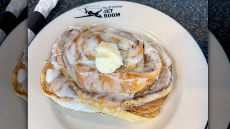 a cinnamon roll pancake with icing and butter on a plate