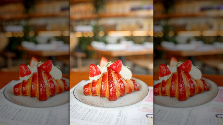 Strawberry croissant on plate, topped with berries and cream