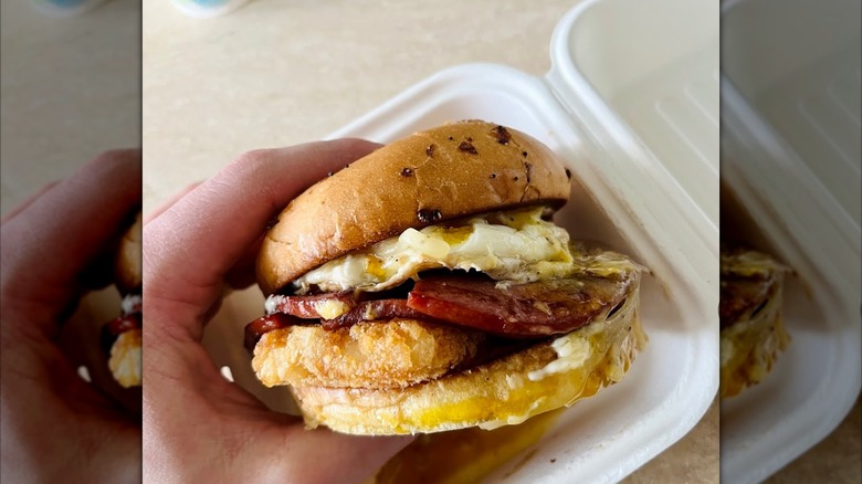 Breakfast sandwich being held over a package