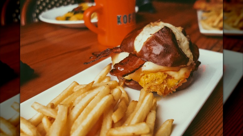 a pretzel breakfast sandwich with fries on a table