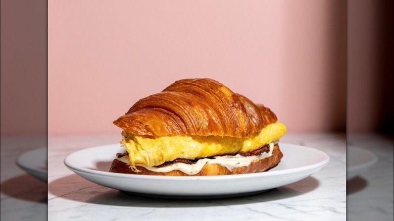 Croissant breakfast sandwich with a pink background