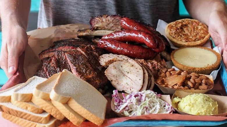 person holding stacked bbq platter