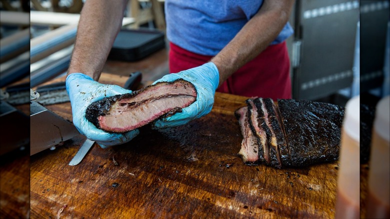 Lewis Barbecue man with gloved hands holding brisket