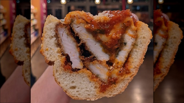 Hand holding chicken Parmesan sandwich