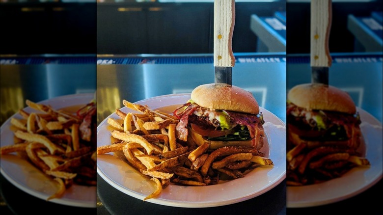 Chicken Parmesan sandwich with knife in it and fries on plate